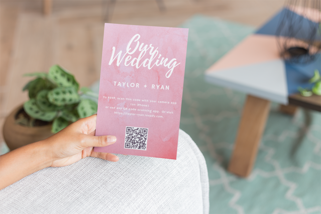 Hand holding paper wedding invitation directing guests to online rsvp